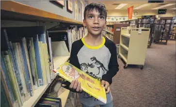  ?? Tomas Ovalle For The Times ?? NICOLAS MALDONADO picks a book at the library in McFarland, Calif. “We have nothing else here for kids. ... You take this out, kids either stay home bored or go out on the streets,” said his mother, Angie Maldonado.