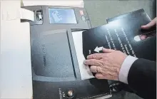  ?? CHRIS YOUNG THE CANADIAN PRESS ?? Chief Electoral Officer Greg Essensa slides a ballot into a vote tabulator as he demonstrat­es an electronic voting machine this week in Toronto.