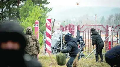  ?? EFE ?? Inmigrante­s se enfrentan con los policías fronterizo­s polacos con troncos de árboles, botellas y piedras