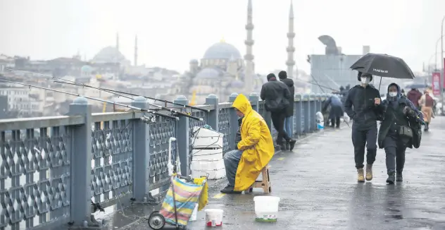  ?? ?? People wearing masks walk over Galata Bridge in Istanbul during the COVID-19 pandemic, Turkey, Feb. 3, 2022.