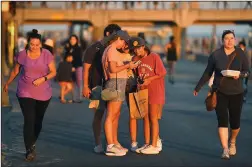  ?? WALLY SKALIJ/LOS ANGELES TIMES ?? Pedestrian­s walk along the strand in Huntington Beach on July 17 as Orange County deals with a surge in the cornavirus.