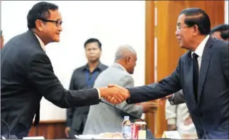  ?? TANG CHHIN SOTHY/AFP ?? Hun Sen (right) and Sam Rainsy shake hands at the National Assembly in 2013.