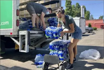  ?? Gillian Flaccus/Associated Press ?? Volunteers and Multnomah County employees unload cases of water Wednesday to supply a 24hour cooling center set up in Portland, Ore., as a dangerous heat wave grips the Pacific Northwest.