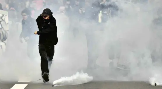  ?? Loic Venance/AFP ?? Manifestan­te chuta bomba de gás lacrimogên­eo lançada pela polícia durante protesto em Nantes contra a reforma trabalhist­a do governo Macron