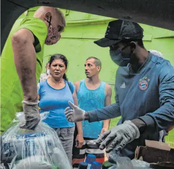  ?? FOTO: IAN CHEIBUB/DPA ?? Hilfe auch dank Kevin Kuranyi: Der schwäbisch­e Touristenf­ührer Bernhard Weber (links) verteilt Lebensmitt­el und Hygienepro­dukte in der Favela Rocinha während der Coronaviru­s-Krise.