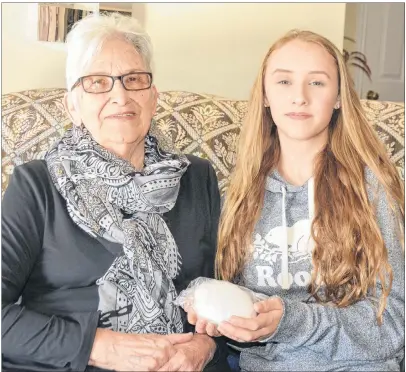  ?? ETHAN PAQUET/JOURNAL PIONEER ?? Mae and Alecia Arsenault admire the snowball Mae kept in her freezer for 11 years, a gift from her granddaugh­ter.