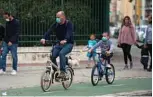  ??  ?? A man and a child wearing face masks, ride bicycles in Seville.