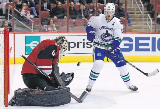  ?? — THE ASSOCIATED PRESS ?? Arizona Coyotes goalie Mike Smith, left, makes a save in front of Vancouver Canucks forward Daniel Sedin, but Smith a rough stretch in the second period when the Canucks scored three times in less than four minutes to secure a 4-1 victory.