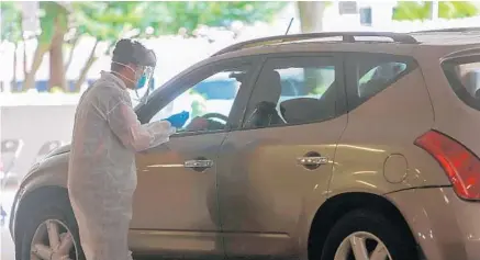  ?? JASON BEEDE/ORLANDO SENTINEL ?? A medical employee at Aventus Biolabs completes a test on a patient inside UCF’s Garage A drive-thru testing site on Monday.