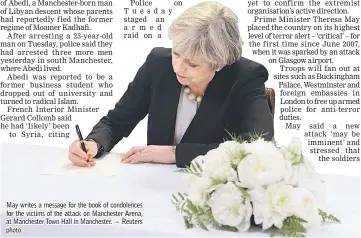  ??  ?? May writes a message for the book of condolence­s for the victims of the attack on Manchester Arena, at Manchester Town Hall in Manchester. — Reuters photo