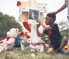  ??  ?? LUTO. Un niño escribe unas palabras en la cruz de una de las víctimas de Parkland, Florida. AFP