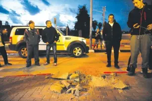  ?? (Flash 90) ?? ISRAELIS STAND near a hole in Sderot caused by a Gaza rocket yesterday.