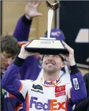  ?? COLIN E. BRALEY - AP ?? Denny Hamlin (11) holds the trophy for winning a NASCAR Cup Series race at Kansas Speedway in Kansas City, Kan., Sunday.