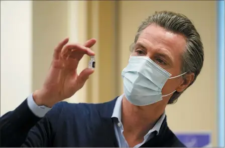 ?? THE ASSOCIATED PRESS ?? California Gov. Gavin Newsom holds up a vial of the Pfizer-BioNTech COVID-19 vaccine on Dec. 14, 2020, at Kaiser Permanente Los Angeles Medical Center in Los Angeles.