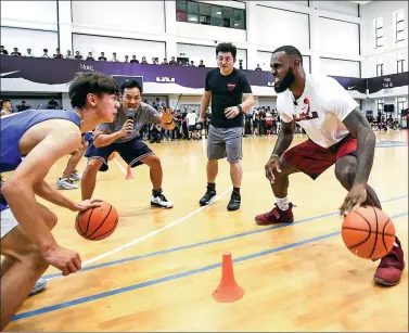  ?? PROVIDED TO CHINA DAILY ?? LeBron James faces off against a Chinese student during a dribbling drill at the High School Affiliated to Shanghai Jiao Tong University