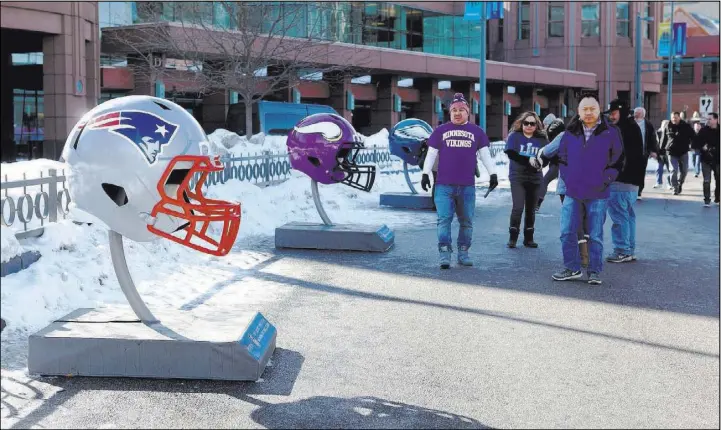  ?? Heidi Fang Las Vegas Review-Journal @HeidiFang ?? Football fans check out helmets of, from left, the New England Patrots, Minnesota Vikings and Philadelph­ia Eagles as they walk to the NFL Experience on Friday in Minneapoli­s.