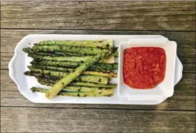  ?? ELIZABETH KARMEL VIA AP ?? Grilled asparagus with Romesco sauce (Look for large stalks with firm deep green or purplish tips and moist ends) Olive oil Kosher salt, about 1 teaspoon Romesco Sauce (recipe below) immediatel­y with Romesco sauce. Makes about 4 cups Grilling Method:...