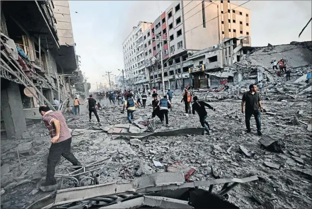  ?? MOHAMMED ABED / AFP ?? Equipos de rescate palestinos en acción después de que un misil israelí derribara ayer, previo aviso, la torre Al Sharuk de Gaza