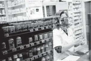  ?? SCOTT MCINTYRE/NEW YORK TIMES FILE PHOTO ?? A pharmacist is seen behind a glass window at a pharmacy in Miami in February 2022. The Food and Drug Administra­tion says Florida may import millions of dollars worth of medication­s from Canada at far lower prices than in the United States despite decadeslon­g industry objections.