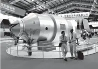  ?? Associated Press ?? ■ In this Nov. 16, 2010, file photo, visitors sit beside a model of China's Tiangong-1 space station at the 8th China Internatio­nal Aviation and Aerospace Exhibition in Zhuhai in southern China's Guangdong Province.