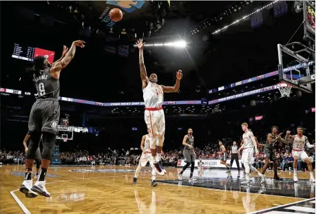  ?? FRANK FRANKLIN II / AP ?? Nets forward DeMarre Carroll shoots over Hawks center Dewayne Dedmon on Sunday. “By the time we catch up in the second quarter, the third quarter comes around and it happens again. We just got to come out with a better energy,” says Dedmon about the team’s defensive struggles.