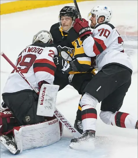  ?? Peter Diana/Post-Gazette ?? Penguins right winger Bryan Rust crashes into Devils goaltender Mackenzie Blackwood on Sunday at PPG Paints Arena.