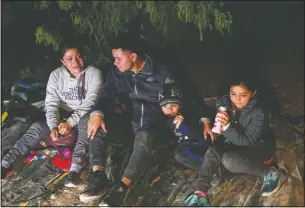  ?? (AP/Dario Lopez-Mills) ?? A family from Honduras sits on the ground after they were smuggled on an inflatable raft across the Rio Grande in Roma.