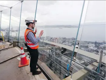  ?? ELAINE THOMPSON/THE ASSOCIATED PRESS ?? Space Needle facilities and constructi­on superinten­dent Matt Waffle looks out over Elliott Bay through newly-installed glass panels atop the Space Needle in Seattle.