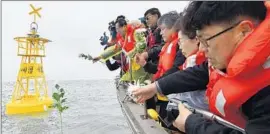  ?? Yonhap News Agency ?? FAMILY MEMBERS of the Sewol ferry victims toss flowers at the site of the sinking off the South Korean coast as the anniversar­y of the disaster approaches.