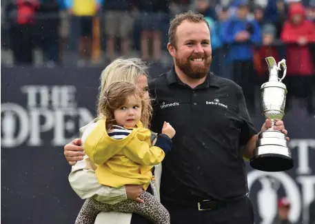  ?? GETTY IMAGES ?? GRAND PRIZE: Ireland’s Shane Lowry holds the claret jug in the rain with his wife and daughter after winning the British Open yesterday at Royal Portrush Golf Club in Northern Ireland. Lowry beat Tommy Fleetwood by 6 shots.