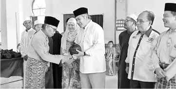  ??  ?? Awang Tengah, flanked on Dayang Morliah and Henry (second right), hands over buffalo meat to the villagers in Ulu Merapok.