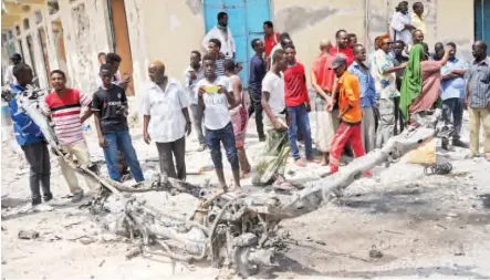  ??  ?? People look at the wreckage of a vehicle near the presidenti­al palace in Mogadishu, Somalia yesterday, after two car bombs were detonated and three Shabaab gunmen were shot dead after exchanging fire with security forces AFP