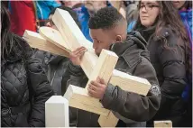  ?? ASHLEE REZIN/CHICAGO SUN-TIMES ?? Colin Clark, 12, kisses a cross for his father, 55-year-old Lazane Clark, during a march in Chicago on Saturday. Lazane Clark was shot to death in February.