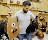  ?? . — AFP ?? Ali Khalifeh, a lute-maker, checks the instrument­s at a shop in the Syrian capital Damascus