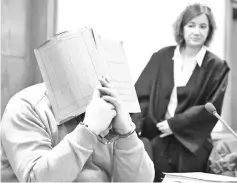  ?? — AFP photo ?? In this file photo Hoegel hides his face behind a folder as he waits next to his lawyer Ulrike Baumann for the opening of another session of his trial at a court in Oldenburg, northweste­rn Germany.