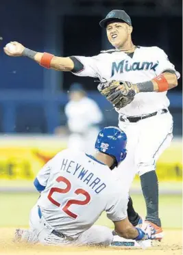  ?? MICHAEL REAVES/GETTY ?? The Marlins’ Starlin Castro turns a double play as the Cubs’ Jason Heyward slides into second base in the eighth inning at Marlins Park on Tuesday night in Miami.