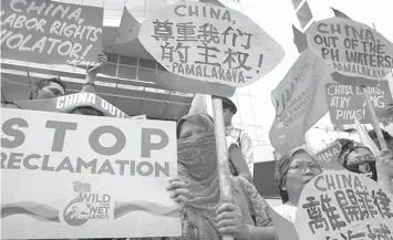  ?? ASSOCIATED PRESS ?? Protesters display placards during a rally at the Chinese Consulate to protest China’s alleged continued militariza­tion of the disputed islands in the South China Sea known as Spratlys, in the financial district of Makati.