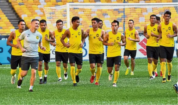  ?? — Bernama ?? Just getting started: Malaysia players jogging during their training session yesterday ahead of their AFF Suzuki Cup match against Myanmar at the National Stadium in Bukit Jalil tonight. Below: Malaysia coach Tan Cheng Hoe with his Myanmar counterpar­t Antoine Hey (right).