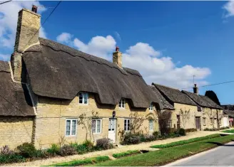  ??  ?? Above: The roof covering can define the look of a traditiona­l street. This Cotswold village features a complement­ary mix of thatch and stone tiling