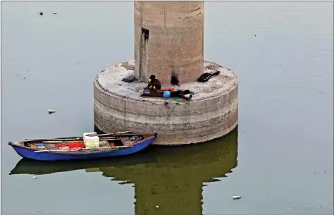  ?? Men rest on a pillar of a bridge over the river Ganga on a hot summer day in Allahabad on Saturday. ??