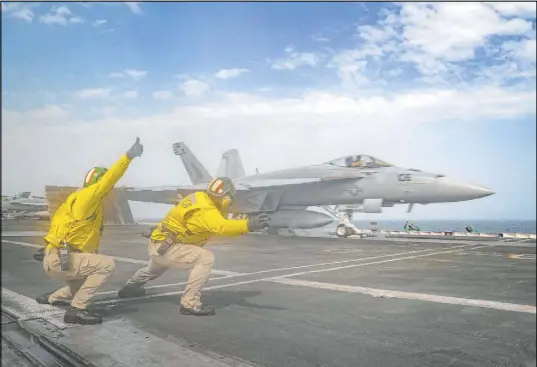  ?? U.S. Navy The Associated Press ?? Lt. Nicholas Miller, from Spring, Texas, and Lt. Sean Ryan, from Gautier, Miss., launch an F/A-18 Super Hornet on Thursday from the deck of the USS Abraham Lincoln in the Arabian Sea.