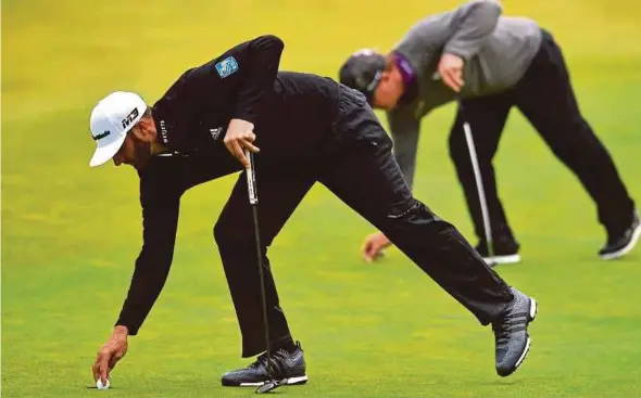  ?? AFP PIC ?? Dustin Johnson (left) retrieves his ball as Charley Hoffman places his during their second rounds at Carnoustie on Friday.