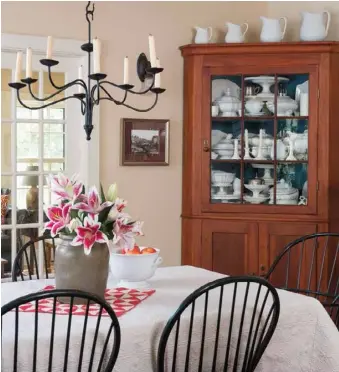  ??  ?? Above: A corner cupboard bought at an antiques show is the perfect backdrop for a gathering of ironstone in the dining room. A graduated parade of evenly spaced pitchers across the top provides a simple and serene contrast to the many stacked and nested pieces inside.