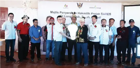  ??  ?? Chen (left) in a symbolic handing-over of the Sares ownership to Long Ukok headman Christophe­r Pusu, witnessed by Dr Abdul Rahman (centre), Dennis (fifth right), Gerawat (fifth left) and others.