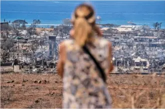 ?? PHOTOS BY GO NAKAMURA/THE NEW YORK TIMES ?? A woman surveys the widespread destructio­n Friday in Lahaina, Hawaii. The search for people killed in the wildfire, and the effort to identify the 96 found so far, has moved slowly.