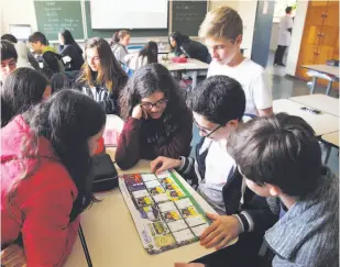  ?? Photos by Andre Penner / Associated Press ?? Students look at a World Cup sticker book during their Portuguese class in Sao Paulo, Brazil. The books have been huge sellers in the U.S. as well.