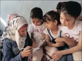  ??  ?? Syrian orphan Noor Ghanem, 13, left, helps other orphans from Aleppo, as they study at the orphanage in Jarablus.