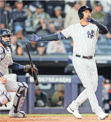  ??  ?? The Yankees’ Aaron Hicks, right, watches his three-run home run against the Astros in Game 5 of the American League Championsh­ip Series on Friday night at Yankee Stadium in New York.