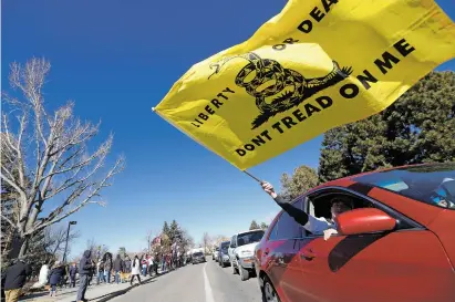  ?? PHOTOS BY LUIS SÁNCHEZ SATURNO/THE NEW MEXICAN ?? A supporter of President Donald Trump waves a flag during a rally Wednesday outside the state Capitol.