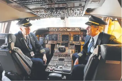  ?? Andy Cross,The Denver Post ?? United Airlines pilots Capt. Tom Spratt, left, and Dean McDavid enjoy time in the cockpit of the Boeing 747 parked Thursday at Concourse B at Denver Internatio­nal Airport.